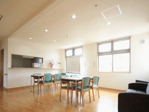 リビングにはゆったり寛げる大きなソファが設置されている。また、キッチンカウンターが設けられていて、カウンターの上には花が飾られている。