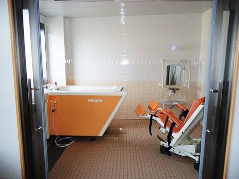 介護用の浴槽が完備されている、清潔感のあるタイル張りの浴室