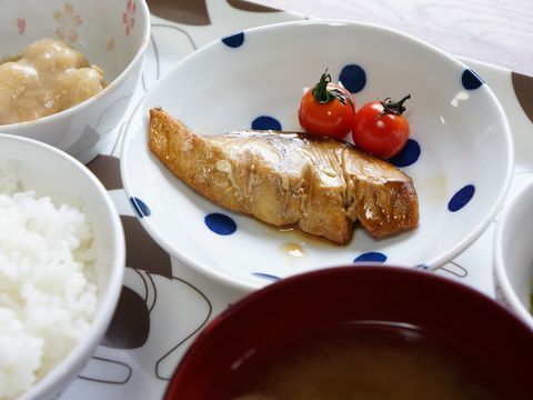 手作りの健康を考えた献立になっている。魚の照り焼きとミニトマト、里芋の煮付けとご飯や味噌汁などが並ぶ。