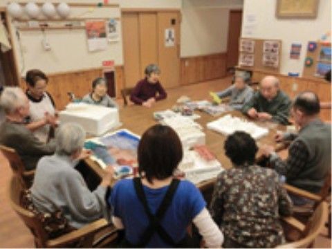 大きなテーブルを囲んで創作を楽しむスタッフと入居者様たち
