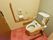 トイレには、左右に肘置き兼手すりが付いている介護用便座が設置され、壁には立ち姿勢にも対応できるＬ字型の手すりと非常ボタンが付けられている。