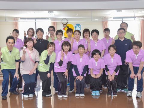 施設内で写真撮影をする、制服を着た笑顔のスタッフたち