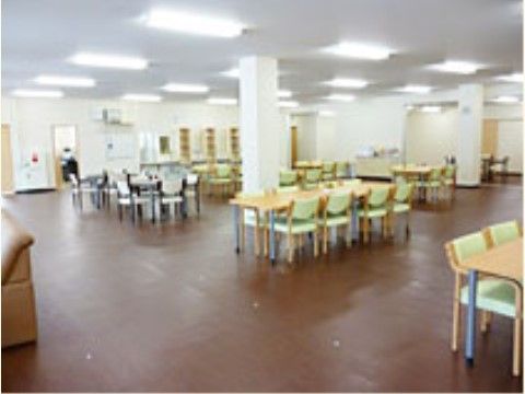 広々としたスペースの中に、テーブルと手すり付きの椅子が設置されている。壁と天井は白色系で、天井には十分な照明設備が設けられている。