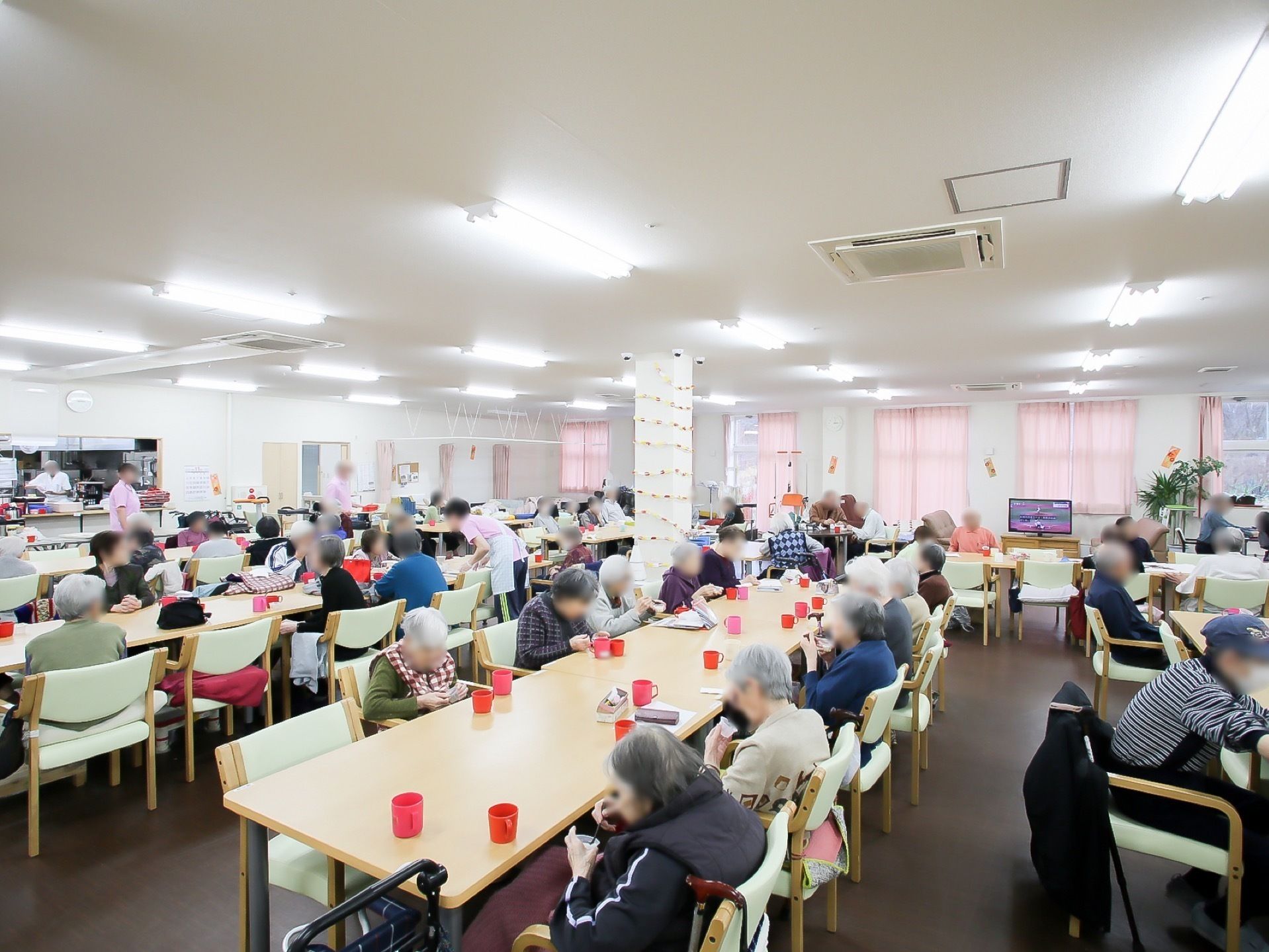 大きな食堂で顔を合わせながら、おやつやお茶を楽しむ入居者様たち