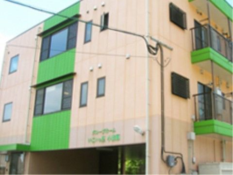 緑色が特徴的な外壁で、２階以上にはベランダが設けられている建物