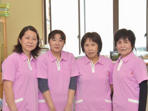 並んで写真に写る、ピンク色の制服を着た４人の女性スタッフ