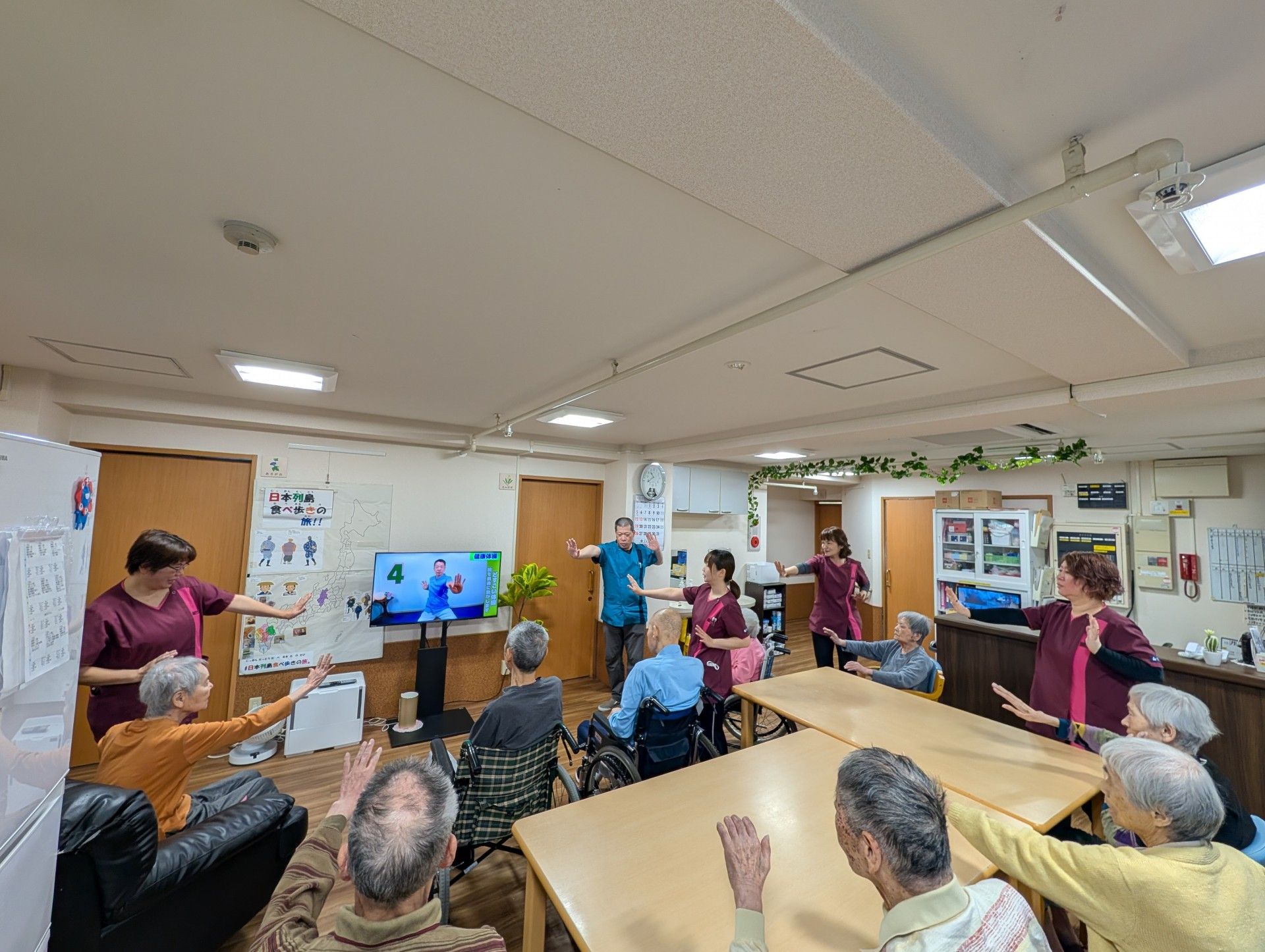 両手を広げて笑顔で写る、エプロンを着た４人の女性スタッフ