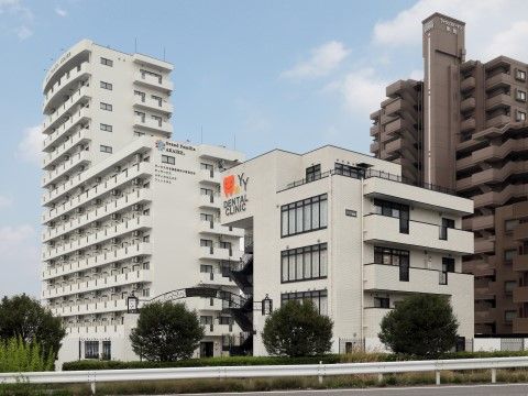 茶色の高層マンションの横に建つ、白を基調とした大きなグループホーム