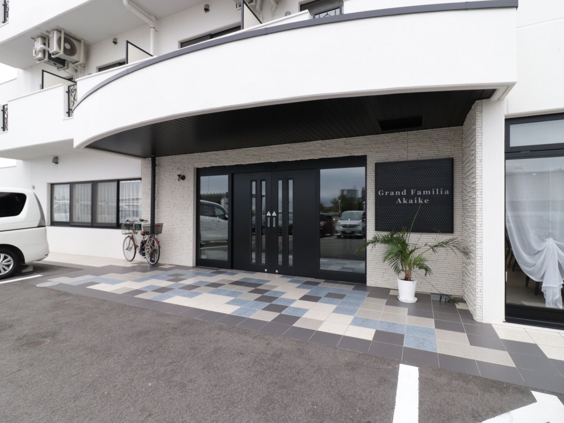 ダークブラウンと白でまとめられた施設の前面。向かって右側にアルファベットで書かれた施設名の看板が掛かっている。