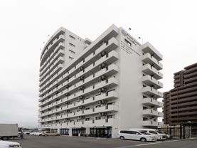 白亜の高級マンションを思わせる施設の外観。14階建てのうち9階までは建坪一杯に、10階以上は約半分の面積上を占めている。