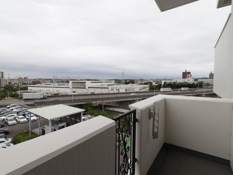 居室に設けられたベランダから眺めた風景。自動車道がほぼ水平の位置に見え、その向こうに建物、遠くには山が見える。