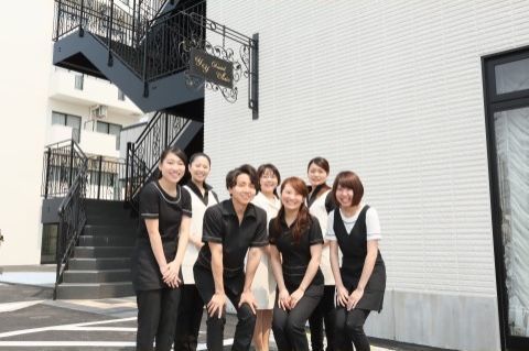 階段の前で写真撮影をする、白や黒の制服を着た男女スタッフ