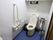 掴まって座ったり立ったりできるように介護用の手すりがトイレの両脇についている。壁には緊急呼び出しボタンが取り付けられている。