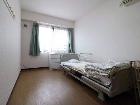 施設利用者が過ごす部屋には介護用のベッドと収納のための引き出しが置いてある。また快適に過ごせるようにエアコンが取り付けられている。