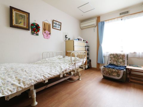 介護用のベッドや収納する引き出し、椅子、テーブルなど施設利用者が暮らすための部屋である。他にもエアコンが設置されている。