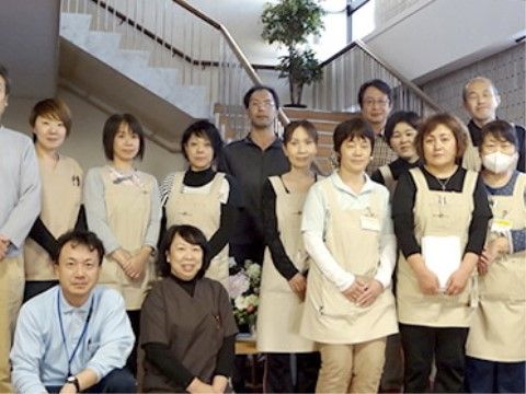 手を前に組んで優しく微笑んで写る、男女スタッフたち