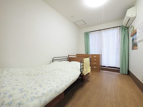 介護ベッドや収納ダンスが置かれた、ワンルームの居室