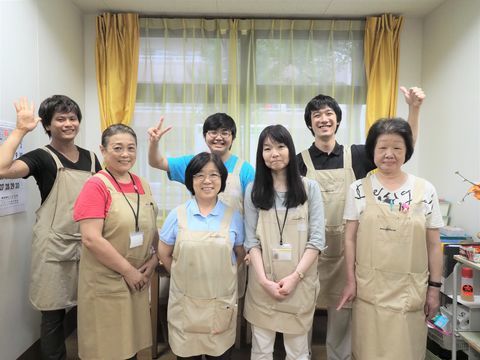 笑顔で写る、半袖にベージュのエプロンを着用したスタッフたち