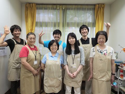 事務室に集まり楽しそうに写真撮影する７人のスタッフたち