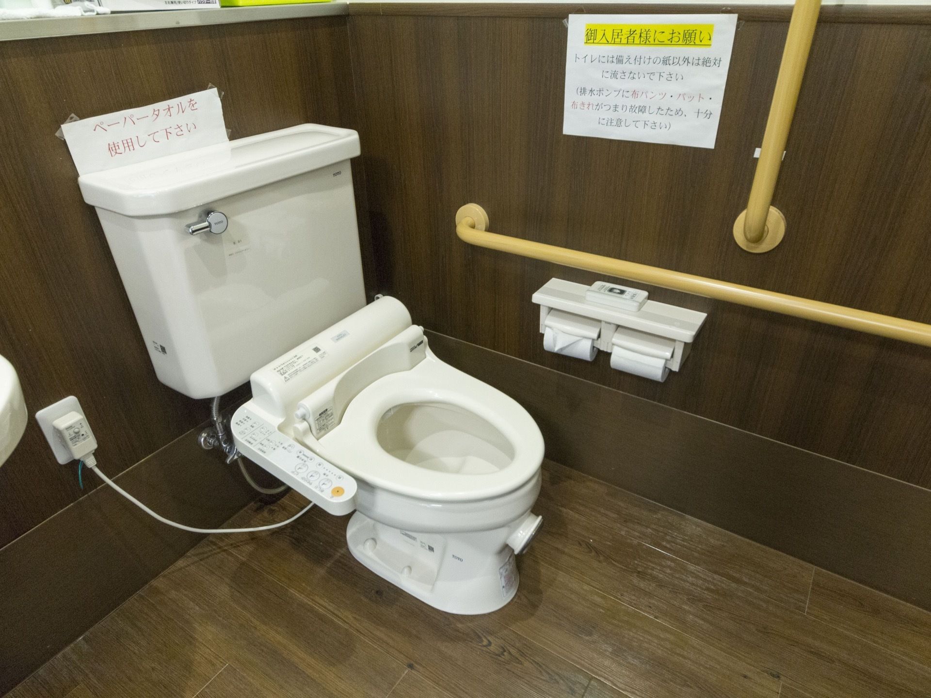 便器の横には十分な長さの木製の手すりが設置されており、入居者様は一連の動作を握ったまま行うことが可能である。