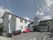 白い外壁と三角屋根の一般住宅のような２階建ての建物である。アスファルトで整備された敷地に２台の車が停められている。