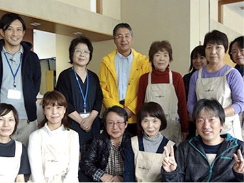 エプロンや名札をつけて集合写真に収まっているスタッフたち
