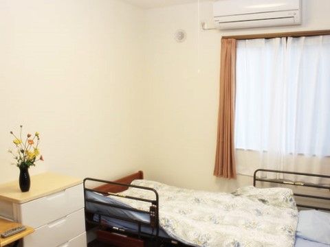 ベッド横にある収納ケースの上に花瓶が置かれている居室