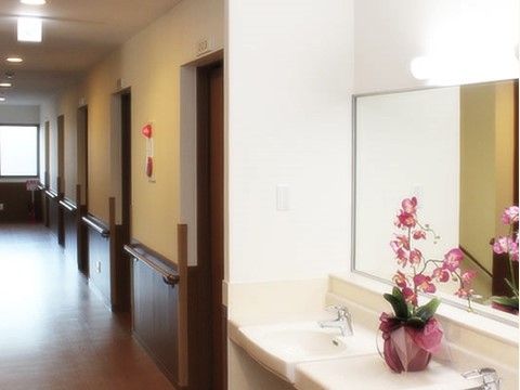 居室ドアの並びに洗面コーナーがある。シングルレバー水栓で正面に鏡がある。下が空いているので車椅子でも利用しやすい。