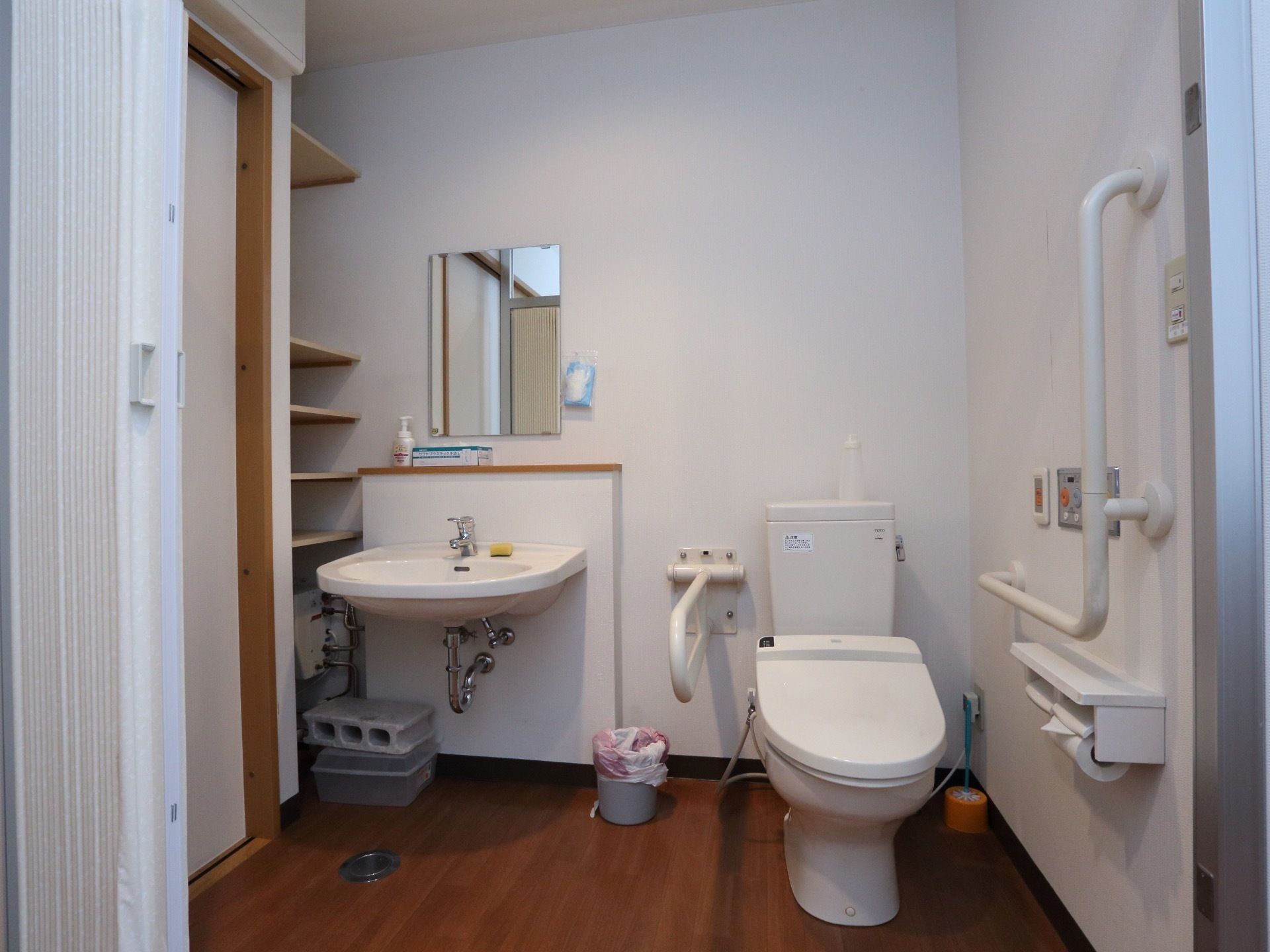 各個室のトイレには、手すりと洗面台が設置されている。居室スペースとは段差がなく、白いカーテンで仕切られている。