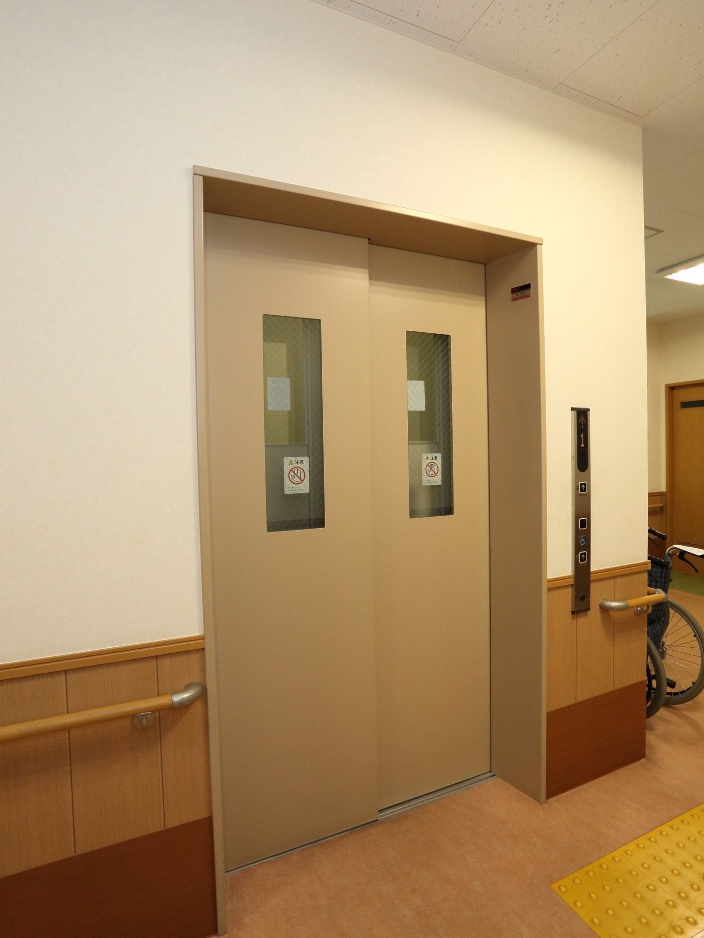 エレベーターまでの通路には、点字ブロックと手すりが設置されている。扉には窓がついているので、中の様子が分かる。