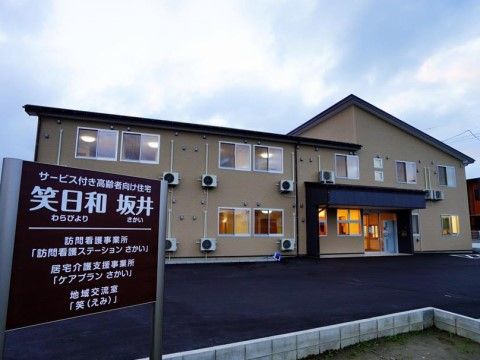 ベージュ色の外壁が特徴の２階建ての建物である。駐車場が広いため、来訪者様は気軽に自動車でお越しいただける。