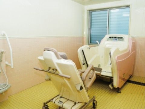 黄色いタイルの浴室に座ったままで入浴ができる浴槽が置かれており、さまざまな入居者様のニーズに応えられる。