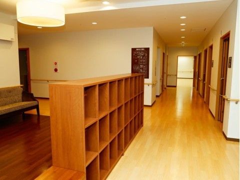 統一感のある上品な廊下には手すりやベンチが置かれている。程よく落とされた照明が落ち着きと暖かさを感じさせる。