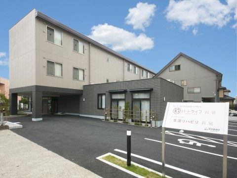 玄関前に大きな車寄せがある、３階建ての施設の全景外観