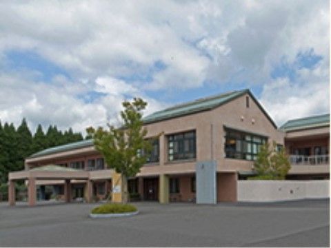 後ろに背の高い木々が生えている、のどかな場所に立地している施設