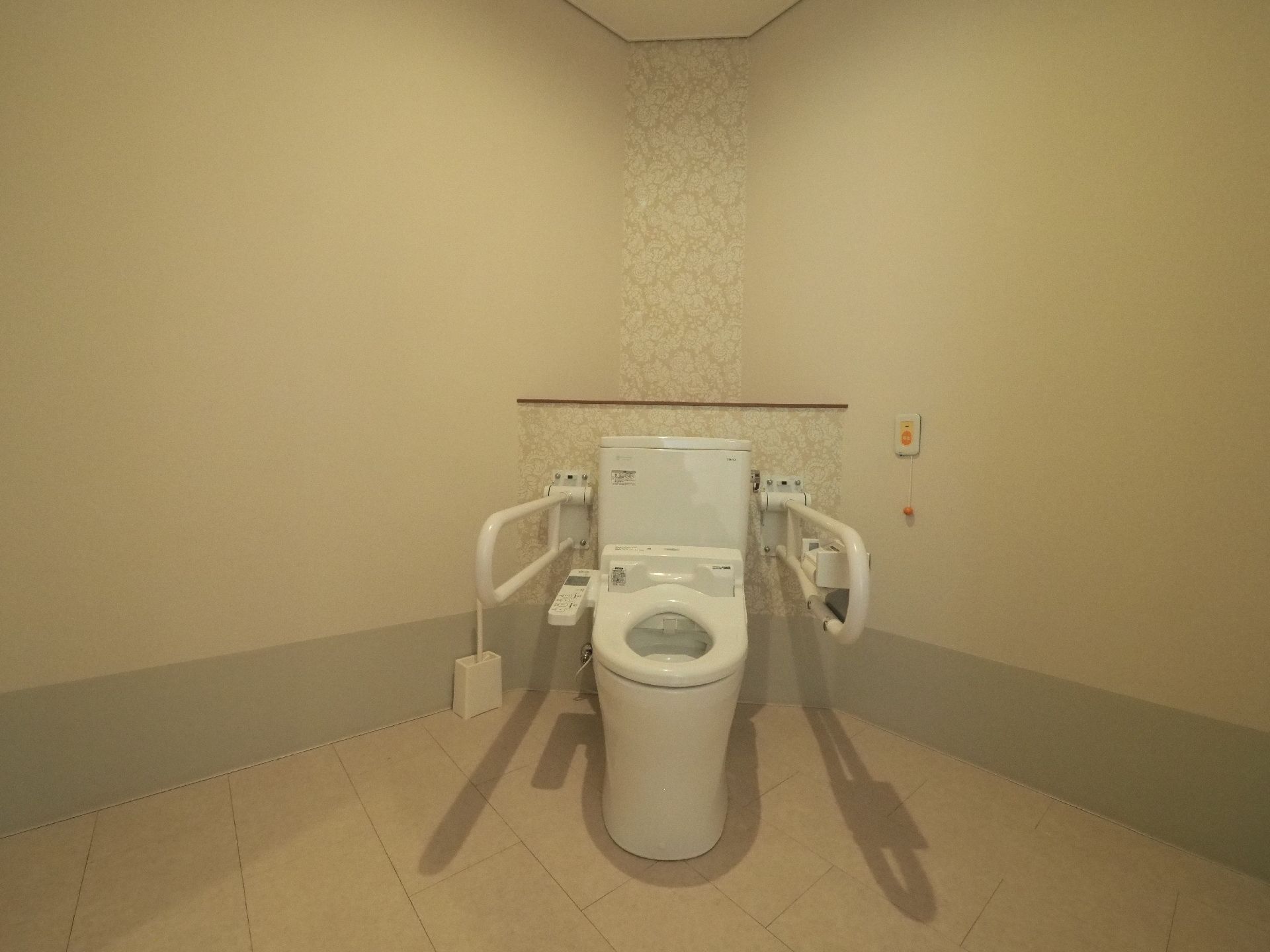 フロア内トイレは、 角に便座を設置する事により広さを確保している。手すりや緊急通報装置が設置され、安全に配慮されている。
