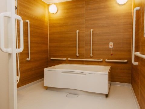 浴槽の周囲の壁に縦横方向の多くの手すりが設置されている浴室