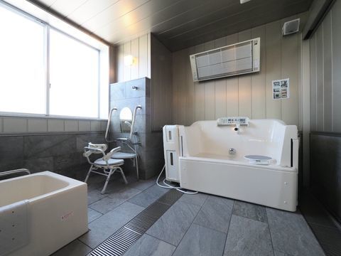 足の不自由な方でも、ゆっくり浴槽に入れる回転いすのついた浴槽がある。明るくて広い、清潔感のある浴室。