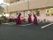 施設前の駐車場。フラダンスの衣装を着た３人の女性が踊っている。周囲には太鼓や銅鑼などの楽器が置かれている。