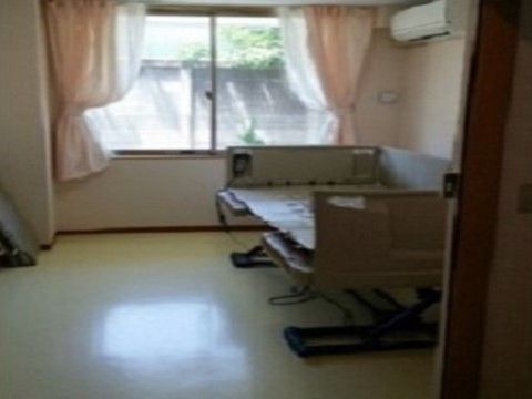 壁際に介護ベッドが置かれ、その上部にエアコンが設置されている居室