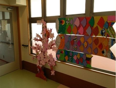 窓一面に貼り付けられた大中小のこいのぼりの写真。ウロコはすべて違う色の色紙が貼られており、色鮮やかである。