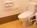 明るい床色のトイレである。壁側にＬ字型の手すり、反対側にも可動式の手すりを備えており、安心して利用することができる。