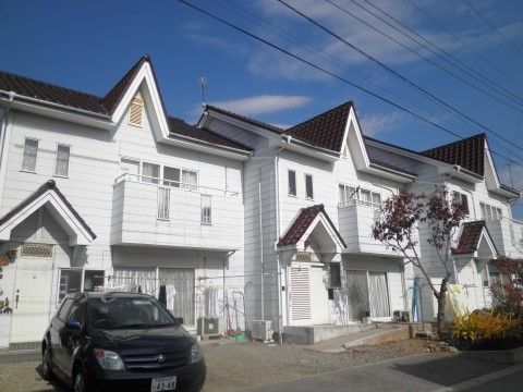 茶の屋根が映える真っ白な外観の建物が並んでいる。２階建てで所々ベランダ部分が張り出している。玄関には三角屋根がついている。