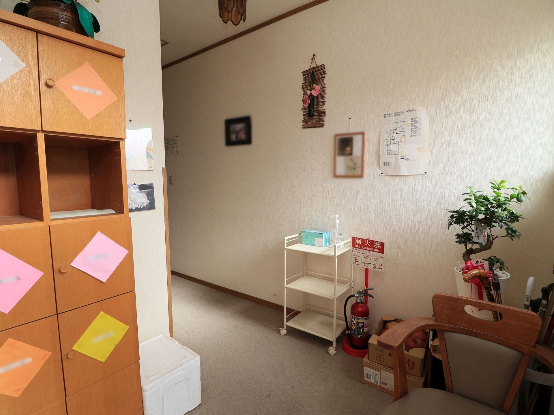 玄関には木製の靴箱が備えつけられており、椅子が置かれている。壁には写真や施設内の地図が貼りつけられている。