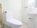 淡いピンク色の床、白色の壁につくられたトイレである。トイレットペーパーホルダーは、洗面台の扉に付いている。