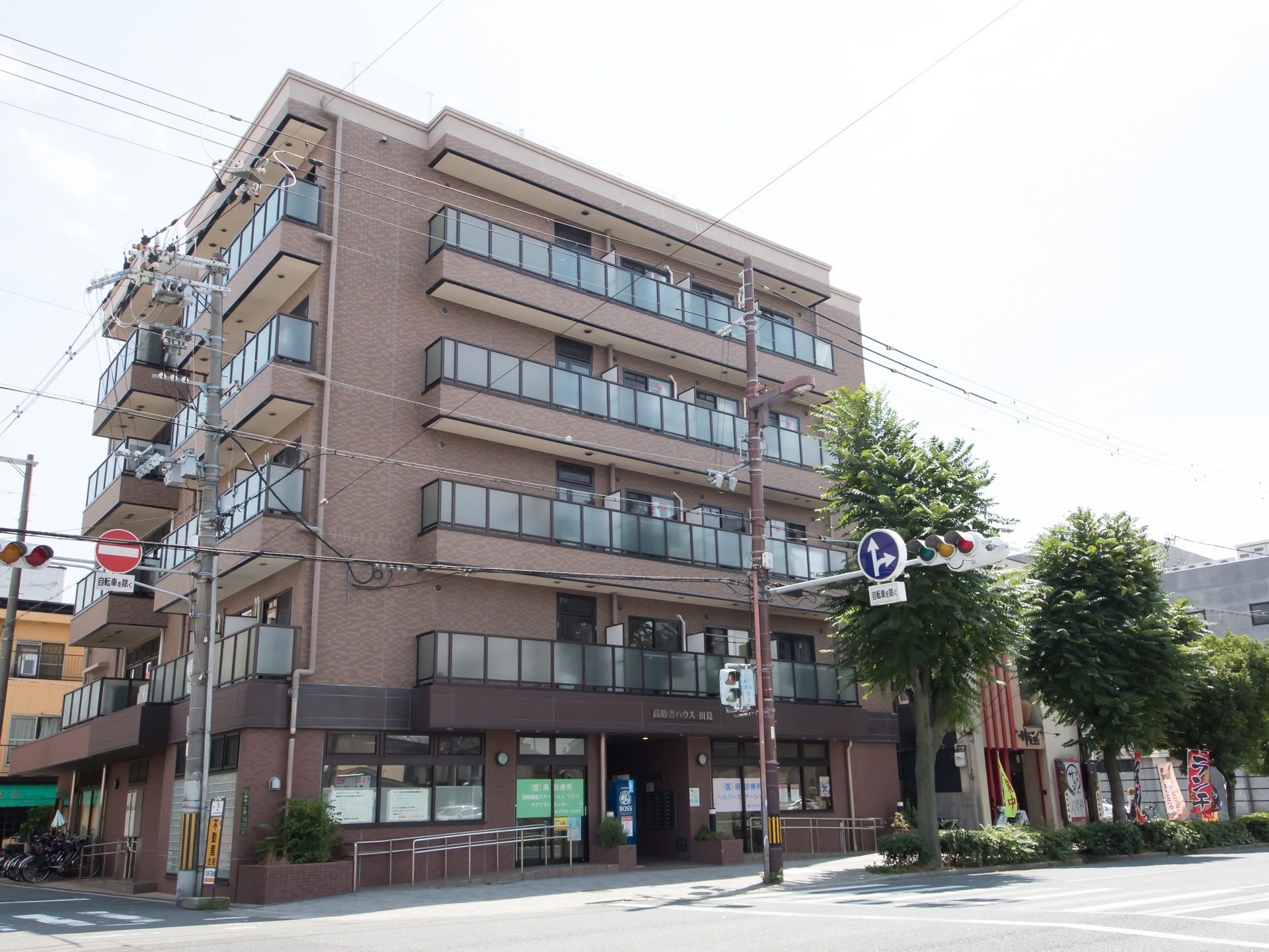 レンガ色の外壁が落ち着いた佇まいの、鉄筋５階建ての建物。集合住宅風のデザインが周囲の町並みに馴染んでいる。