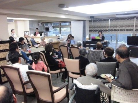 広いスペースに並べられた多くの椅子に座り、訪問演奏に耳を傾ける入居者様たち