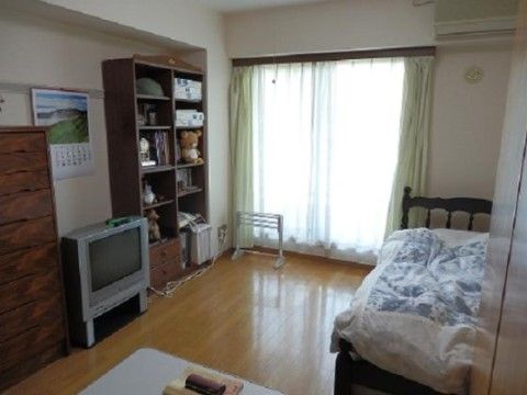 高さのある本棚や衣類収納棚の間にテレビが置かれている居室