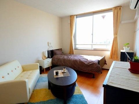 腰高の窓からの採光でとても明るく、ソファやローテーブルも置かれている居室