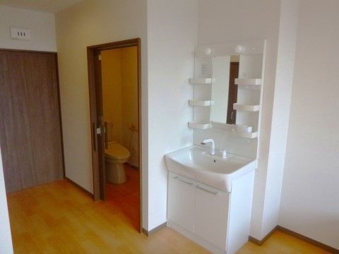 白い壁が清潔感のある居室は、トイレの隣に棚付きの洗面化粧台がある。床は埃が溜まりにくい木目調のフローリング仕立てになっている。